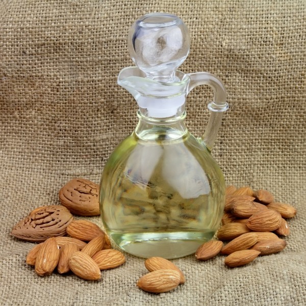 A bottle of almond oil with nuts on the linen texture